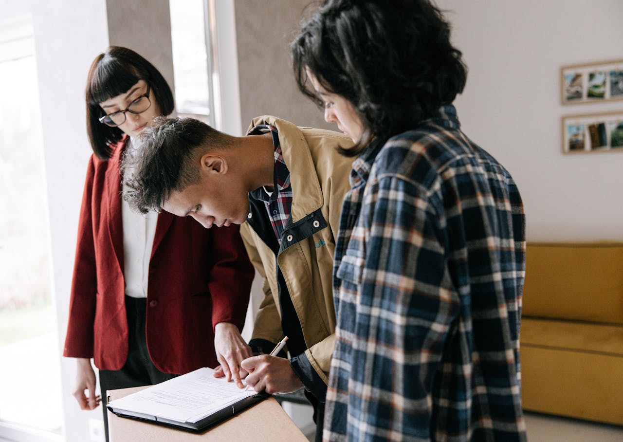 why-choose-us Young couple signing a real estate agreement with an agent indoors.